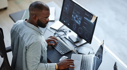 Minimal high angle view at African American software developer working with computers and data systems in office